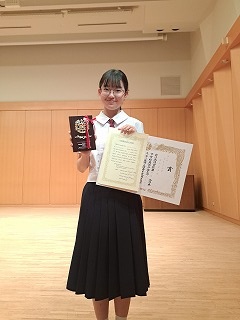 賞状と表彰楯を持った奥村茉由さん