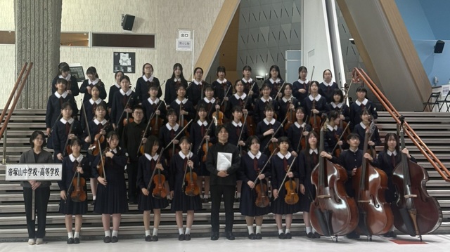 楽器を持った弦楽部の生徒部員および担当教員の集合写真