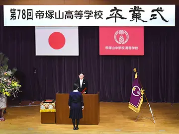 卒業証書を受け取るために校長の前に立っている女子生徒