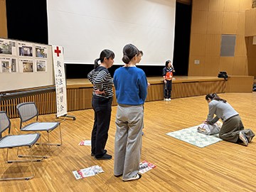 指導員の指導のもと、女子教員が模型を使って蘇生方法をやっている姿