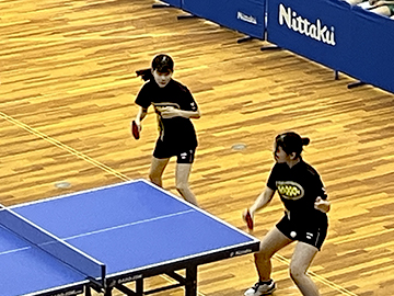 卓球台前でラケットを女子選手2人の姿