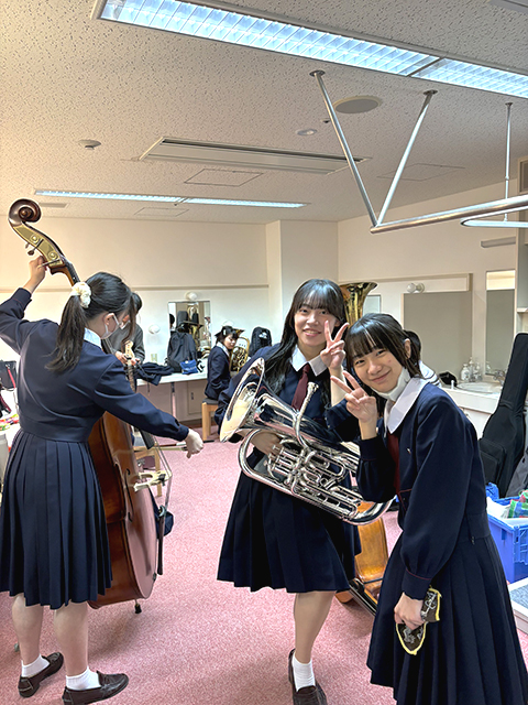 控室で練習の合間ピースする女子生徒2人
