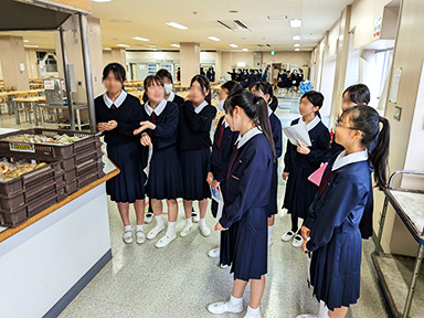 食堂内のパンの前で案内する複数の中学三年生女子