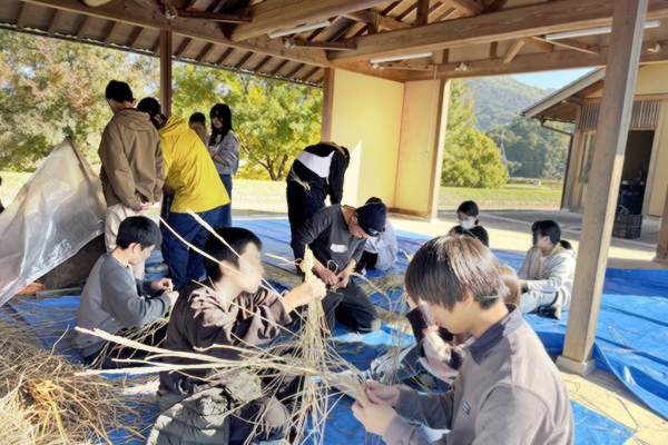 生徒みんなで座ってしめ縄作りしている