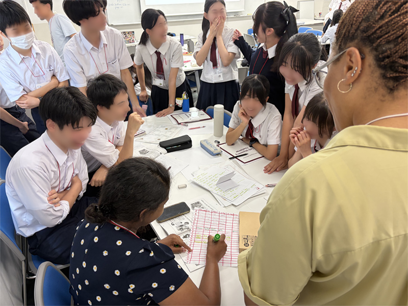 男子6名と女子6名が笑顔で先生が記入している表を見ている