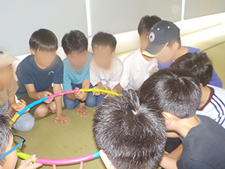ゲームするためのカラフルな輪っかを持つ生徒達